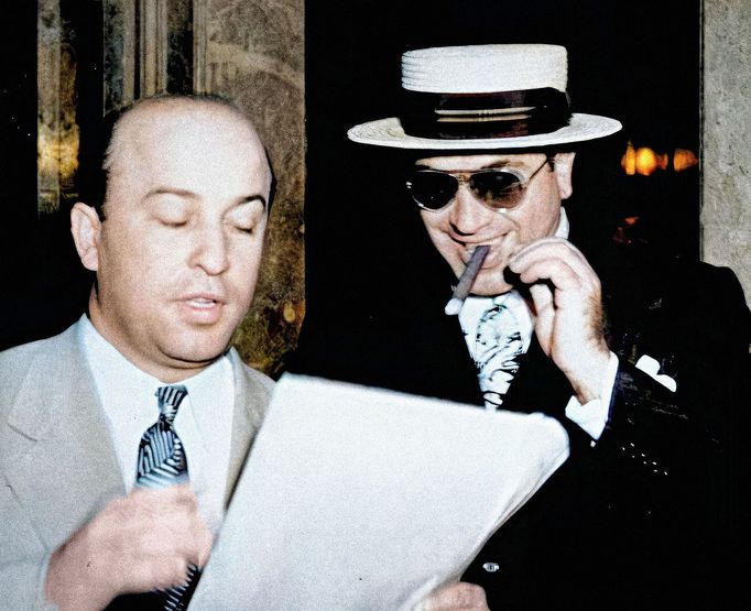 Al Capone kouří doutník a poslouchá, jak jeho advokát Abe Teitelbaum vysvětluje právní fáze vládního daňového případu. Kolorováno.