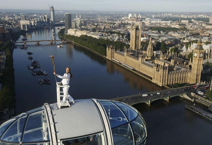 Torch bearer Amelia Hempleman-Adams, age 17, stands on top of a capsule on the London Eye as part of the torch relay ahead of the London 2012 Olympic Games in London July 22, 2012. REUTERS/Luke MacGregor (BRITAIN - Tags: SPORT OLYMPICS TPX IMAGES OF THE DAY) Published: Čec. 22, 2012, 7:11 dop.