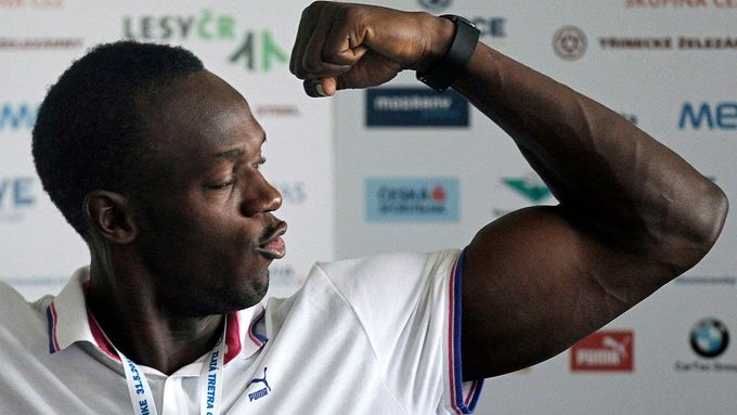 Usain Bolt ukazuje svaly na tiskové konferenci.