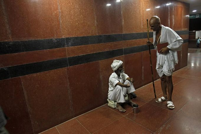 Mahesh Chaturvedi (R), 63, who dresses up like Mahatma Gandhi, talks to a beggar as he walks through a subway in New Delhi September 28, 2012. Chaturvedi says that the soul of Gandhi resides in him and he has been sent to continue the work of Father of the Nation. After his self proclaimed transformation in 2002 as Gandhi, Chaturvedi has been travelling extensively and plays up to his startling resemblance to Gandhi at protests and demonstrations. Picture taken September 28, 2012. REUTERS/Mansi Thapliyal (INDIA - Tags: SOCIETY) Published: Lis. 26, 2012, 3:57 dop.