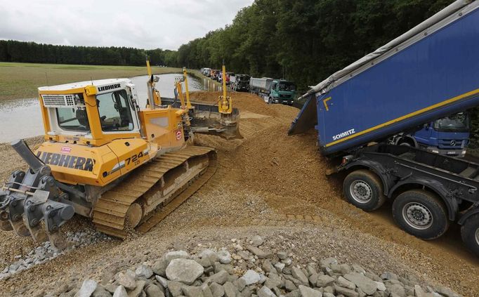 Trucks unload gravel for the reinforcement of weak dikes along the swollen Danube river near the settlement of Altholz some 6km west of the eastern Bavarian city of Deggendorf June 10, 2013. Tens of thousands of Germans, Hungarians and Czechs were evacuated from their homes on Wednesday as soldiers raced to pile up sandbags to hold back rising waters in the region's worst floods in a decade. REUTERS/Wolfgang Rattay (GERMANY - Tags: POLITICS DISASTER)