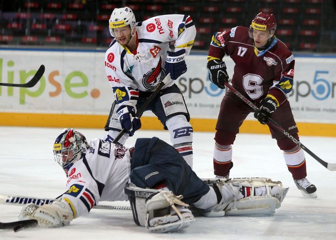 Hokejový brankář Chomutova Milan Řehoř chytá puk před Jaroslava Hlinku v utkání 16. kola Tipsport extraligy 2012/13 proti Spartě Praha.