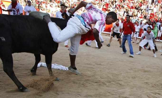 A reveller is tossed by a wild cow during festivities in the bullring following the sixth running of the bulls of the San Fermin festival in Pamplona July 12, 2012. Several runners suffered light injuries in the fastest run (two minutes and twenty seconds) so far in this festival, according to local media. REUTERS/Joseba Etxaburu (SPAIN - Tags: SOCIETY) Published: Čec. 12, 2012, 10:37 dop.