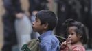 A boy carrying a child stands in front of police officers at a site where a man had been lynched in Tactic, in Alta Verapaz region, some 189 km (117 miles) from Guatemala City, September 12, 2012. According to local media, the man who was lynched and burnt alive by a mob, had entered a school and killed two children, 8-year-old and a 13-year-old, with a machete. REUTERS/Jorge Dan Lopez (GUATEMALA - Tags: EDUCATION CRIME LAW) Published: Zář. 13, 2012, 1:34 dop.