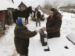 Žena dává hlasovací lístek do urny ve vesnici Okťabrskoje, 440 kilometrů od Moskvy.