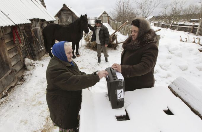 Žena dává hlasovací lístek do urny ve vesnici Okťabrskoje, 440 kilometrů od Moskvy.