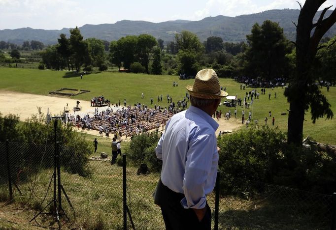 A man watches the torch lighting ceremony of the London 2012 Olympic Games at the site of ancient Olympia in Greece May 10, 2012. REUTERS/Kevin Coombs (GREECE - Tags: SPORT OLYMPICS) Published: Kvě. 10, 2012, 9:39 dop.