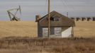 An oil pump jack operates near a vacant farm structure outside Williston, North Dakota, October 19, 2012. Thousands of people have flooded into North Dakota to work in state's oil drilling boom. Picture taken October 19, 2012. REUTERS/Jim Urquhart (UNITED STATES - Tags: ENERGY ENVIRONMENT AGRICULTURE BUSINESS EMPLOYMENT) Published: Říj. 22, 2012, 1:40 odp.