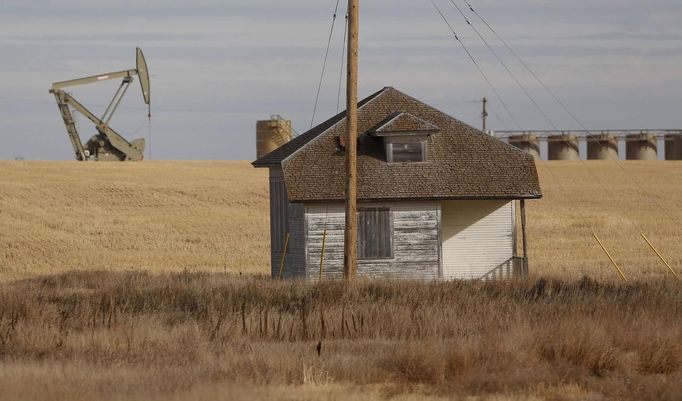 An oil pump jack operates near a vacant farm structure outside Williston, North Dakota, October 19, 2012. Thousands of people have flooded into North Dakota to work in state's oil drilling boom. Picture taken October 19, 2012. REUTERS/Jim Urquhart (UNITED STATES - Tags: ENERGY ENVIRONMENT AGRICULTURE BUSINESS EMPLOYMENT) Published: Říj. 22, 2012, 1:40 odp.