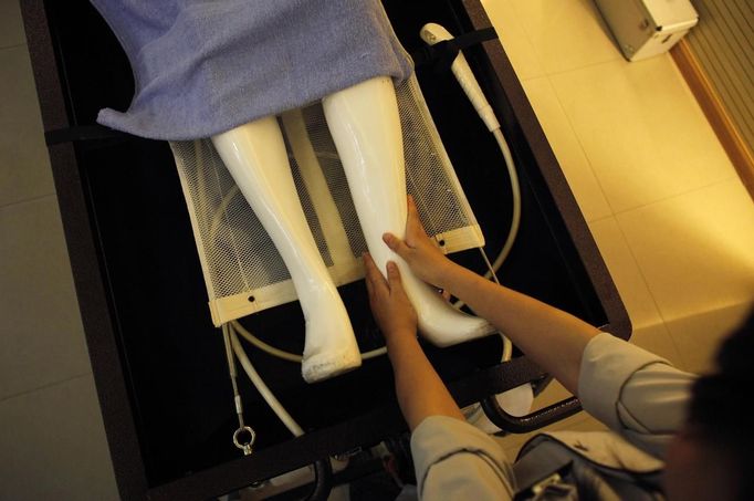 A student massages the legs of a mannequin during an undertaker service class at the Tianquanjiajing Funeral Service school in Jiaxing, Zhejiang province May 29, 2012. A new breed of young Chinese undertakers are fighting centuries-old taboos to gain social acceptance for their profession, saying they help the deceased and their families make their final parting with respect. There are more than 1,500 students across the country studying to become undertakers each year. Courses in funeral services take three years to complete and the service includes washing of the dead body as well as providing funeral make-up and dressing. Picture taken May 29, 2012. REUTERS/Carlos Barria (CHINA - Tags: SOCIETY) ATTENTION EDITORS - PICTURE 12 OF 17 FOR PACKAGE 'FUNERAL SERVICE STUDENTS' Published: Čer. 7, 2012, 2:44 dop.