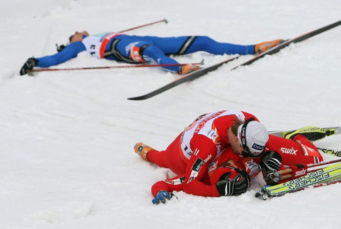 Týmový kolega Johan Kjoelstad v cíli zalehl vyčerpaného Hattestada. V pozadí leží na sněhu Nikita Kriukov z Ruska, který doběhl čtvrtý.