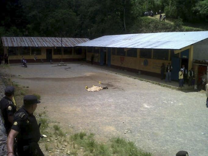 Police officers stand guard next to the body of a student at a primary school in Tactic, in Alta Verapaz region, some 189km (117 miles) from Guatemala City, September 12, 2012. According to local media, a man entered the school and killed two children, one 8-years-old and the other 13, with a machete. The man was later lynched by a mob, who beat him up and burned him alive. REUTERS/Volunteers Firefighters/Handout (GUATEMALA - Tags: EDUCATION CRIME LAW) FOR EDITORIAL USE ONLY. NOT FOR SALE FOR MARKETING OR ADVERTISING CAMPAIGNS. THIS IMAGE HAS BEEN SUPPLIED BY A THIRD PARTY. IT IS DISTRIBUTED, EXACTLY AS RECEIVED BY REUTERS, AS A SERVICE TO CLIENTS Published: Zář. 12, 2012, 8:33 odp.