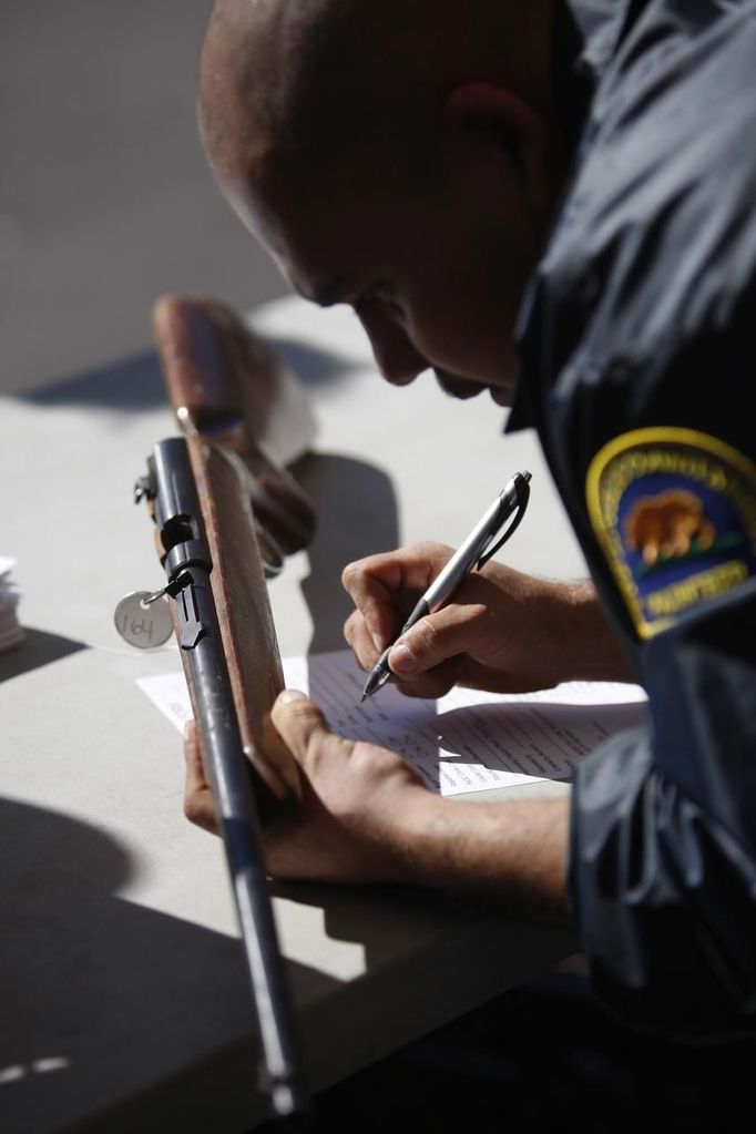 A Los Angeles County Sheriff's volunteer catalogues guns being traded in at the 'Gifts for Guns' gun buyback in Compton, California, January 21, 2013. People can trade in their guns anonymously and with no questions asked in exchange for $200 gift cards for assault weapons, $100 gift cards for shotguns, handguns and rifles, and $50 for non-operational firearms. U.S. President Barack Obama is pushing to address controversial issues surrounding gun violence and regulation as he begins his second term in office. REUTERS/David McNew (UNITED STATES - Tags: POLITICS SOCIETY) Published: Led. 21, 2013, 10:56 odp.