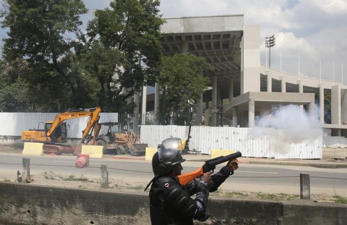 A riot police officer fires tear gas during clashes with supporters of a native Indian community living at the Brazilian Indian Museum protesting against the community's eviction in Rio de Janeiro March 22, 2013. Brazilian military police took position early morning outside the abandoned museum, where the community of around 30 native Indians have been living in since 2006. The community was ordered to leave the museum in 72 hours by court officials since last week, local media reported. Most of the Indians later left the museum after making a deal with the authorities. Pictured at rear is Maracana stadium. REUTERS/Ricardo Moraes (BRAZIL - Tags: CIVIL UNREST POLITICS REAL ESTATE BUSINESS SOCIETY) Published: Bře. 22, 2013, 5:10 odp.