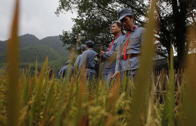 Mid-level government officials dressed in red army uniforms stand in a rice field as they visit an old house where former Chinese leader Mao Zedong use to live, during a five-day training course at the communist party school called China Executive Leadership Academy of Jinggangshan, in Jiangxi province September 21, 2012. China Executive Leadership Academy was established in 2005 by the Central Committee of the Communist Party of China, after the 16th Communist Party Congress in 2002. By the end of August 2012, the academy has held 789 training classes for almost 40,000 people. During the course, trainees listen and sing revolutionary songs, visit old revolutionary sites and review historical communist materials. China has yet to announce the starting date for the 18th Communist Party Congress, China's biggest political meeting in a decade, which will see the transfer of power from President Hu Jintao and Premier Wen Jiabao to a new generation. REUTERS/Carlos Barria (CHINA - Tags: POLITICS SOCIETY) Published: Zář. 21, 2012, 3:18 odp.