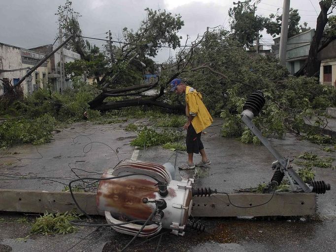 A man walks near a damaged power line in Santiago de Cuba October 25, 2012. Hurricane Sandy grew into a major potential threat to the east coast of the United States on Thursday after hammering Cuba's second-largest city and taking aim at the Bahamas, U.S. forecasters said. Strengthening rapidly after tearing into Jamaica and crossing the warm Caribbean Sea, Sandy hit southeastern Cuba early on Thursday with 105-mph winds that cut power and blew over trees across the city of Santiago de Cuba. Reports from the city of 500,000 people, about 470 miles (750 km) southeast of Havana spoke of significant damage, with many homes damaged or destroyed. According to one Cuban radio report, at least one person was killed, bringing the death toll to at least three after fatalities in Jamaica and Haiti. REUTERS/Miguel Rubiera/Cuban Government National Information Agency - AIN/Handout (CUBA - Tags: ENVIRONMENT DISASTER) FOR EDITORIAL USE ONLY. NOT FOR SALE FOR MARKETING OR ADVERTISING CAMPAIGNS. THIS IMAGE HAS BEEN SUPPLIED BY A THIRD PARTY. IT IS DISTRIBUTED, EXACTLY AS RECEIVED BY REUTERS, AS A SERVICE TO CLIENTS Published: Říj. 25, 2012, 6:02 odp.