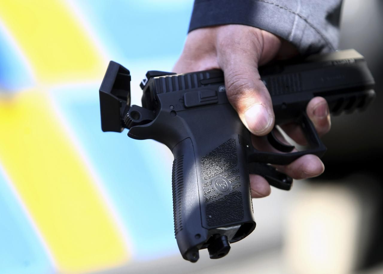 Policejní důstojník drží zbraň, kterou Pavel Vondrouš vystřelil na prezidenta Klause.