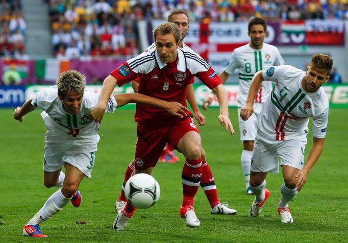 Christian Eriksen se snaží projít přes Fabia Coentraa a Miguela Velosa během utkání Dánska s Portugalskem ve skupině B na Euru 2012.