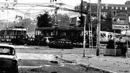 Ohořelé zbytky aut a tramvají stojí na křižovatce v centru Sarajeva po zásahu dělostřeleckou palbou. Květen 1992.