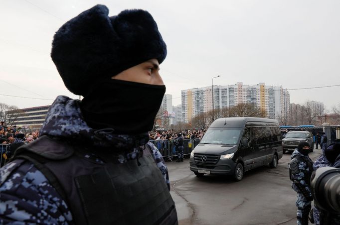 Na příjezd vozu s rakví dohlíželi maskovaní policisté.