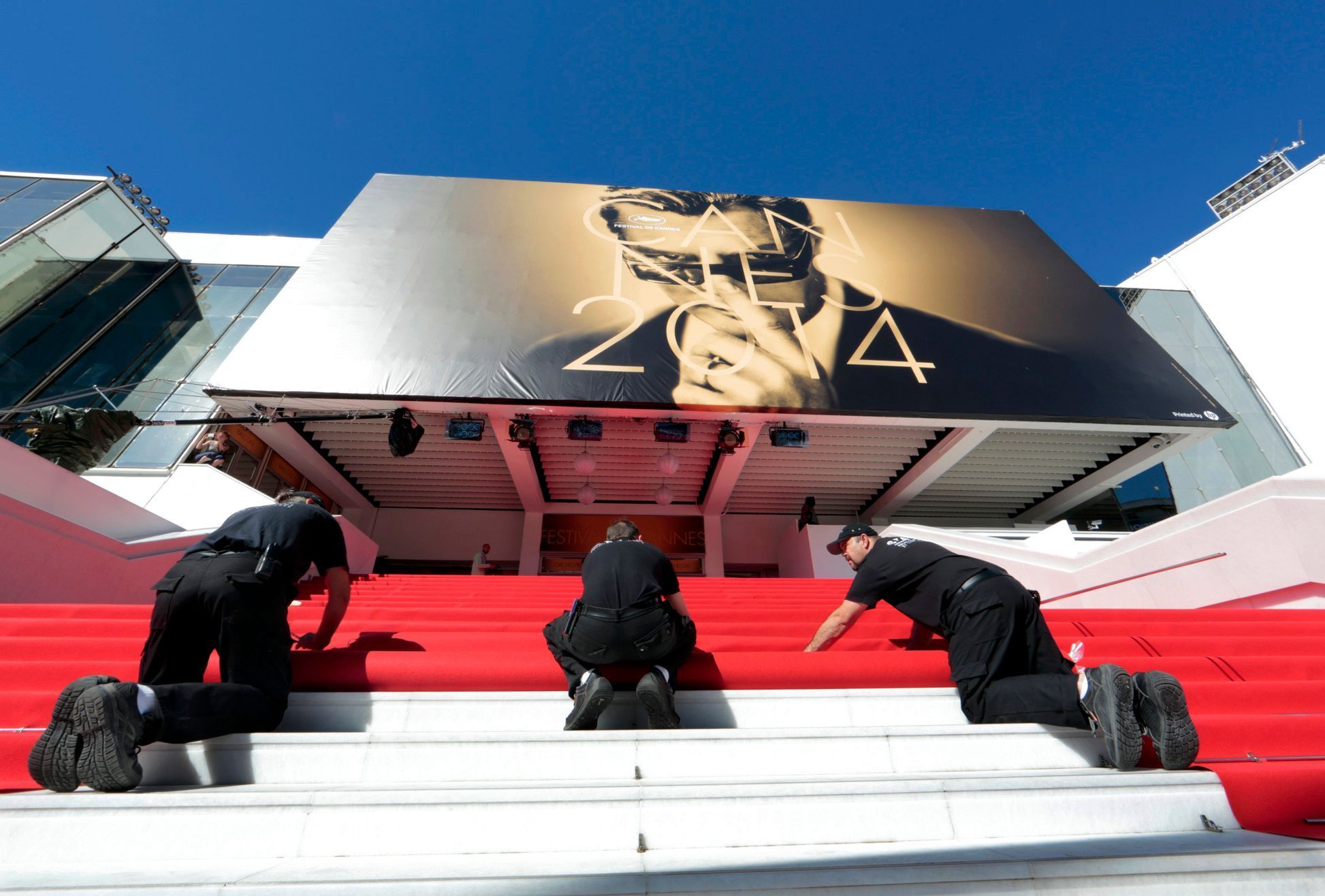 Workers install the red carpet in front of the main entrance of the Festival Palace for the opening ceremony of the 67th Cannes Film Festival in Cannes