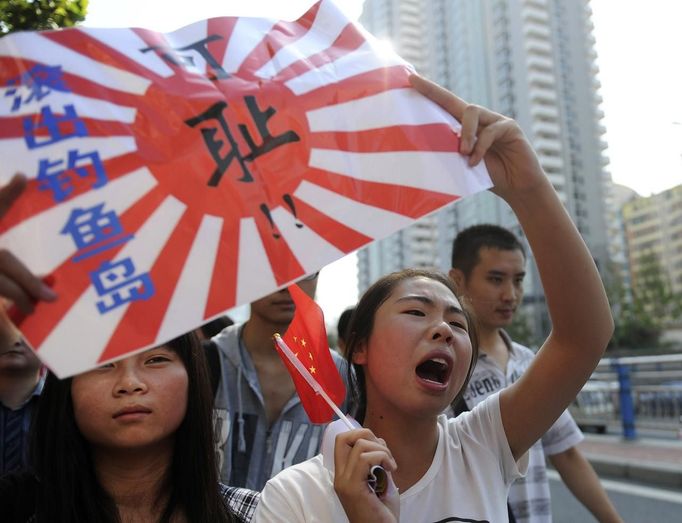 A demonstrator holds a Chinese flag and a placard as she yells slogans during a protest in Hefei, Anhui province, September 15, 2012. Thousands of protesters besieged the Japanese embassy in Beijing on Saturday, hurling rocks and bottles at the building as police struggled to keep control, amid growing tensions between Asia's two biggest economies over a group of disputed islands. The Chinese characters on the placard read, "Get out of Diaoyu Islands." (L) and "Shame on you!" (C) REUTERS/Stringer (CHINA - Tags: POLITICS CIVIL UNREST) CHINA OUT. NO COMMERCIAL OR EDITORIAL SALES IN CHINA