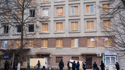 Lidé zabedňují okna nemocnice po ostřelování ve městě Žytomyr.