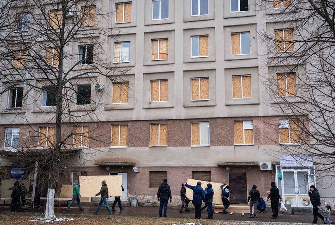 Lidé zabedňují okna nemocnice po ostřelování ve městě Žytomyr.