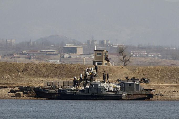 People transport packs of rice at Hwanggumpyong Island located in the middle of the Yalu River, near the North Korean town of Sinuiju and the Chinese border city of Dandong, March 29, 2013. China called for an easing of tensions on Friday as North Korea put its missile units on standby to attack U.S. military bases in South Korea and the Pacific after the United States flew two nuclear-capable stealth bombers over the Korean peninsula. REUTERS/Jacky Chen