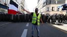 Protestující v žluté vestě drží francouzskou národní vlajku před francouzskou pořádkovou policií CRS během demonstrace v Paříži.