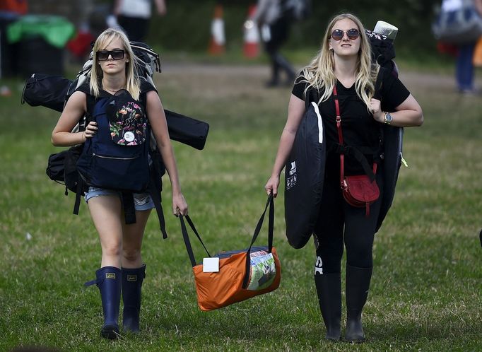 Revellers carry their belongings as they arrive for the Glastonbury Festival