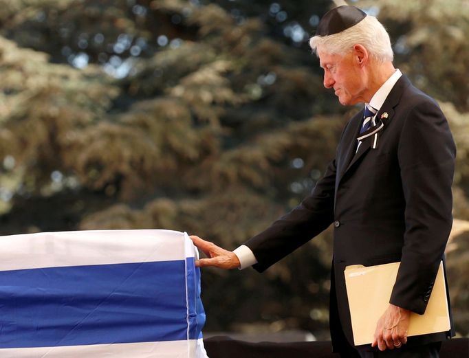 Bill Clinton u rakve pokryté státní vlajkou.