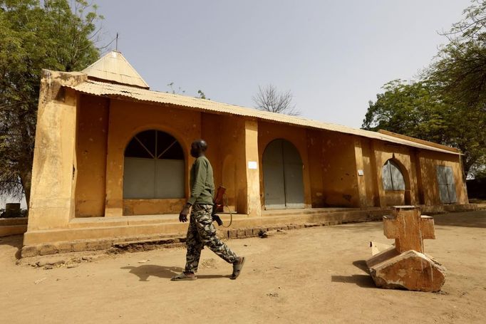 A Malian soldier walks away from a cross believed to be removed by Islamist rebels from the church seen in the background in the recently liberated town of Diabaly January 24, 2013. REUTERS/Eric Gaillard (MALI - Tags: CIVIL UNREST CONFLICT MILITARY RELIGION POLITICS) Published: Led. 24, 2013, 6:07 odp.