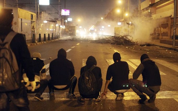 Protesters opposing Egyptian President Mohamed Mursi and the Muslim Brotherhood sit in a line facing police vehicles after police fired tear gas at protesters near the Presidential Palace in Cairo February 11, 2013. Protesters demanding the departure of Mursi clashed with police outside his palace on Monday on the second anniversary of the overthrow of veteran autocrat Hosni Mubarak. Dozens of youths threw rocks at the Ettihadiya palace after a peaceful march by thousands of demonstrators who accused Mursi's conservative Muslim Brotherhood of hijacking Egypt's democratic revolution and seeking to monopolise power. REUTERS/Asmaa Waguih (EGYPT - Tags: POLITICS CIVIL UNREST CRIME LAW) Published: Úno. 11, 2013, 8:28 odp.