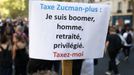 Protestující drží transparent s nápisem „Zdanit Zucman-plus, jsem boomer, muž, důchodce, privilegovaný. Zdaníte mě“ během demonstrace v Paříži.