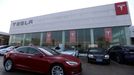 FILE PHOTO: A Tesla car is driven past a store of the electric vehicle (EV) maker in Beijing, China January 4, 2024. REUTERS/Florence Lo/File Photo