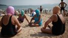 Women, wearing nylon masks, chat as they rest on the shore during their visit to a beach in Qingdao, Shandong province July 6, 2012. The mask, which was invented by a woman about seven years ago, is used to block the sun's rays. The mask is under mass production and is on sale at local swimwear stores. REUTERS/Aly Song (CHINA - Tags: SOCIETY TRAVEL ENVIRONMENT) Published: Čec. 6, 2012, 4:31 odp.