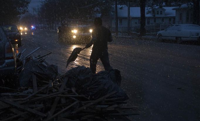 A man clears debris in icy rain from the front yard of his neighborhood which was left destroyed by Hurricane Sandy in the Staten Island borough of New York November 7, 2012. A wintry storm dropped snow on the U.S. Northeast on Wednesday and threatened to bring dangerous winds and flooding to a region still climbing out from the devastation of Superstorm Sandy. The Nor'easter storm added misery to thousands of people whose homes were destroyed by Sandy, which killed 120 people when it smashed ashore on October 29 in the New York-New Jersey area, swallowing entire neighborhoods with rising seawater and blowing homes from their foundations. REUTERS/Adrees Latif (UNITED STATES - Tags: DISASTER ENVIRONMENT) Published: Lis. 7, 2012, 10:43 odp.