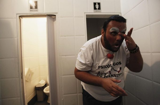 A member of the Traffic Psychologists applies face paint in a toilet of a petrol station in preparation for his performance at a traffic light in Sao Paulo July 23, 2012. Traffic Psychologists is a non-profit non-governmental organization which aims to humanize traffic and reduce the level of stress caused to drivers. Sao Paulo has more than 7 million vehicles, according to figures from the state transport authority Detran. Picture taken July 23, 2012. REUTERS/Nacho Doce (BRAZIL - Tags: TRANSPORT SOCIETY) Published: Čec. 24, 2012, 6:44 dop.