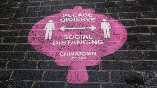 Značka na chodníku v londýnské čtvrti China town nabádá k dodržování bezpečné vzdálenosti mezi lidmi.