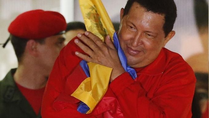 Venezuelan President Hugo Chavez hugs the national flag while celebrating from a balcony at the Miraflores Palace in Caracas October 7, 2012. Venezuela's socialist President Chavez won re-election in Sunday's vote with 54 percent of the ballot to beat opposition challenger Henrique Capriles. REUTERS/Jorge Silva (VENEZUELA - Tags: POLITICS ELECTIONS) Published: Říj. 8, 2012, 5:29 dop.
