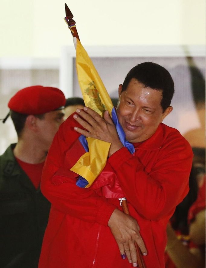 Venezuelan President Hugo Chavez hugs the national flag while celebrating from a balcony at the Miraflores Palace in Caracas October 7, 2012. Venezuela's socialist President Chavez won re-election in Sunday's vote with 54 percent of the ballot to beat opposition challenger Henrique Capriles. REUTERS/Jorge Silva (VENEZUELA - Tags: POLITICS ELECTIONS) Published: Říj. 8, 2012, 5:29 dop.