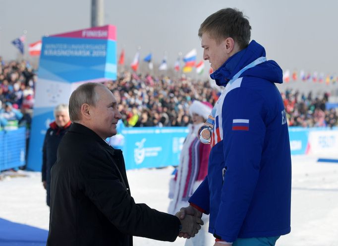 Prezident Vladimir Putin gratuluje na univerziádě při ceremoniálu po závodě běžců na 10 kilometrů ruským sportovcům, kteří obsadili všechna tři místa na stupních vítězů