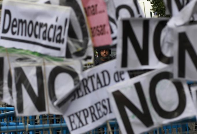 A riot police officer stands behind placards placed on barriers that cordon off the Spanish parliament in Madrid, September 25, 2012. Protesters clashed with police in Spain's capital on Tuesday as the government prepares a new round of unpopular austerity measures for the 2013 budget that will be announced on Thursday. REUTERS/Susana Vera (SPAIN - Tags: CIVIL UNREST POLITICS BUSINESS) Published: Zář. 25, 2012, 9:11 odp.