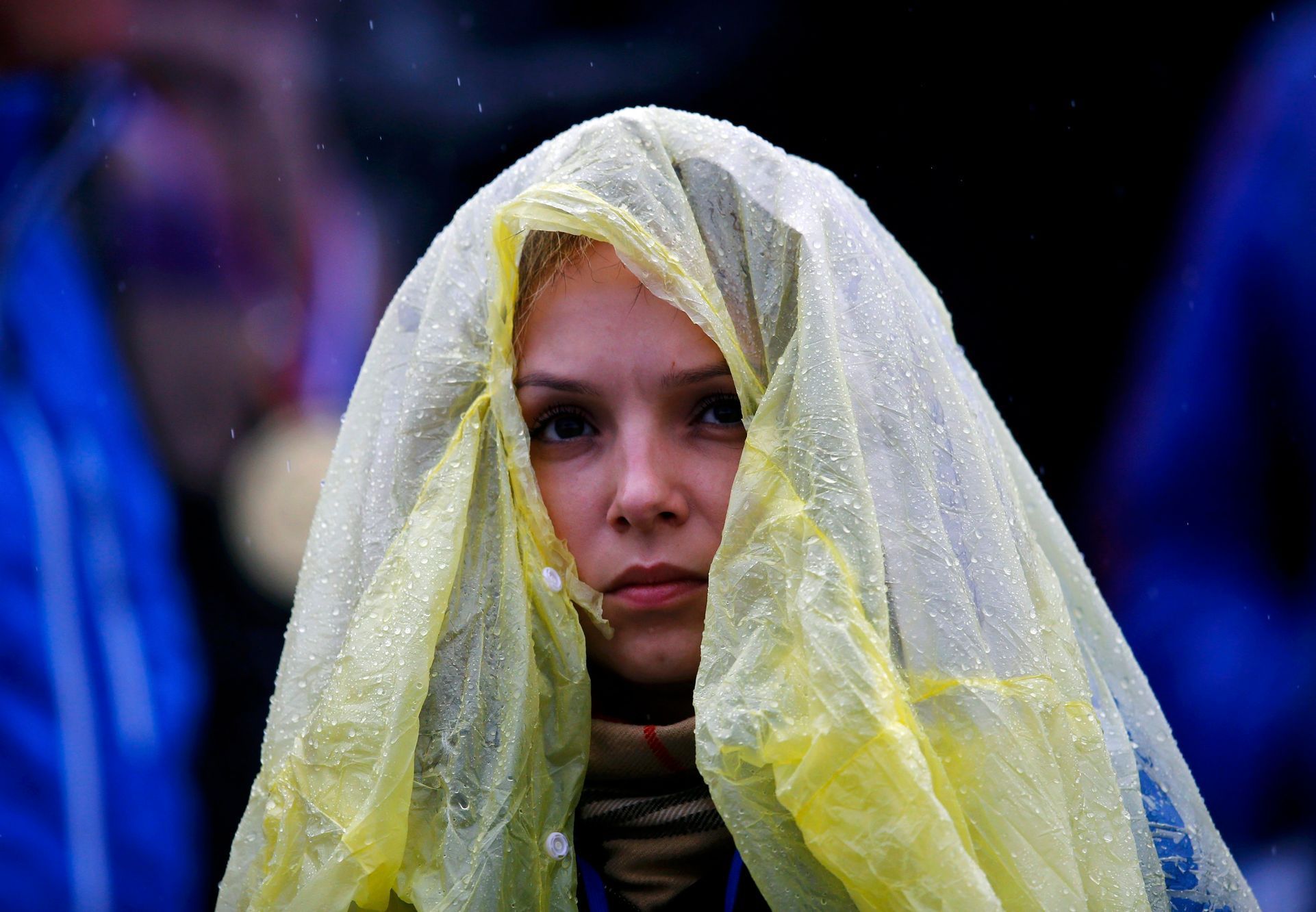 A spectator uses a raincover to protect herself from rain as she waits for the start of second run of the women's alpine skiing giant slalom event during the 2014 Sochi Winter Olympics at the Rosa Khu