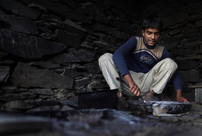 An Afghan youth cooks dinner for members of the Afghan security Group, a local militia force, at Observation Post Mustang in Afghanistan's Kunar Province June 4, 2012. REUTERS/Tim Wimborne (AFGHANISTAN - Tags: CIVIL UNREST CONFLICT MILITARY) Published: Čer. 4, 2012, 4:42 odp.