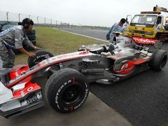 Pracovníci okruhu v Šanghaji se připravují na odtažení McLarenu Lewise Hamiltona, který skončil v kačírku v příjezdu do boxů.