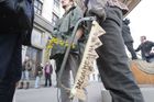 Scházejí se demonstranti s alegorickými předměty.