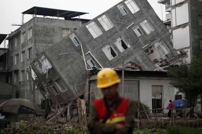 A rescuer walks in front of a damaged building after Saturday's earthquake in Lingguan town of Baoxing county, Sichuan province April 22, 2013. Rescuers struggled to reach a remote, rural corner of southwestern China on Sunday as the toll of the dead and missing from the country's worst earthquake in three years climbed to 208 with almost 1,000 serious injuries. The 6.6 magnitude quake struck in Lushan county, near the city of Ya'an in the southwestern province of Sichuan, close to where a devastating 7.9 quake hit in May 2008, killing 70,000. REUTERS/Aly Song (CHINA - Tags: DISASTER ENVIRONMENT TPX IMAGES OF THE DAY) Published: Dub. 22, 2013, 7:59 dop.