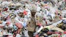 A man collects recyclable cans and bottles at a garbage disposal site near Sanaa